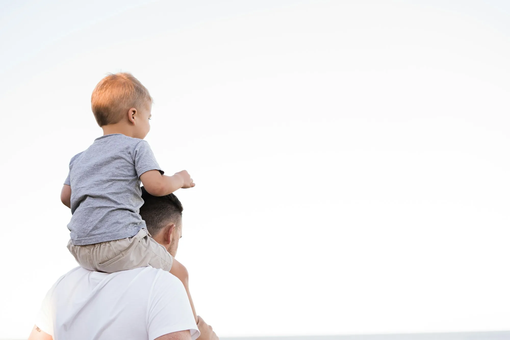 Toddler sitting on a parent's shoulders looking ahead