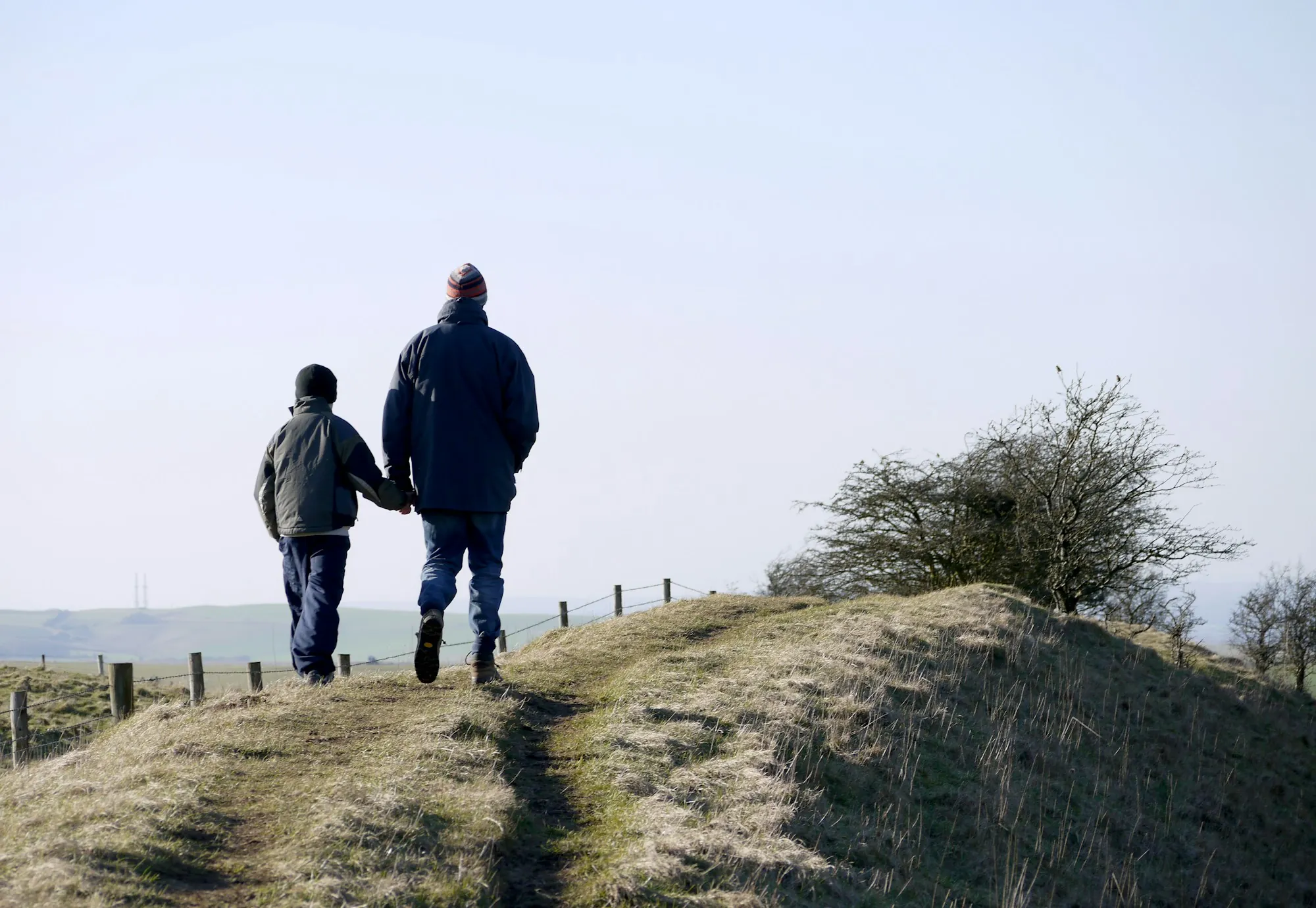 Grandparent and child walking up a grassy hill