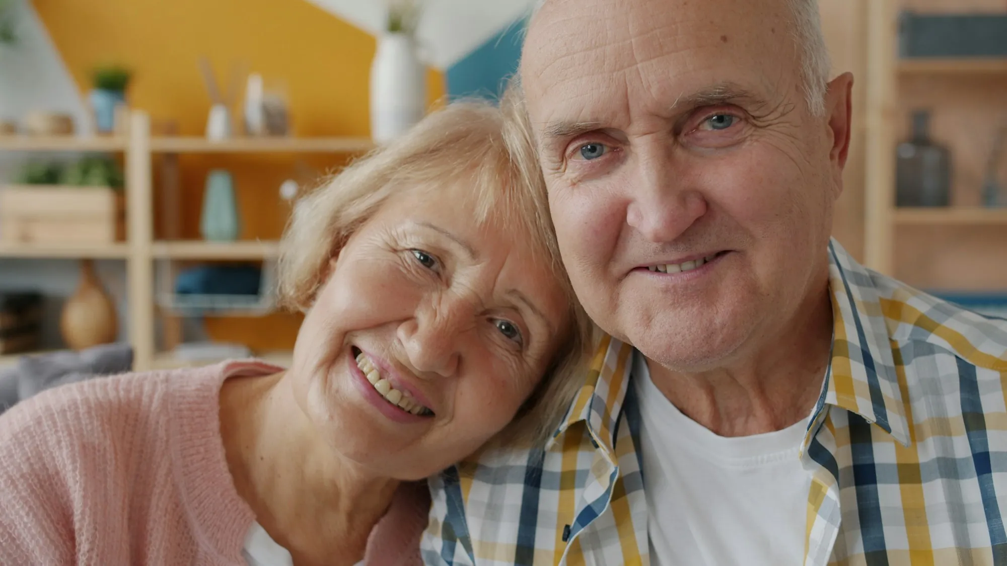 Smiling senior couple cheek to cheek at home